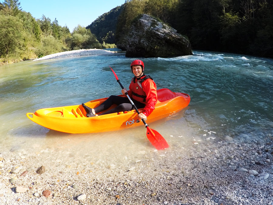 Person in orange sit on top kayak resting on shore of Sava river Bled Slovenia