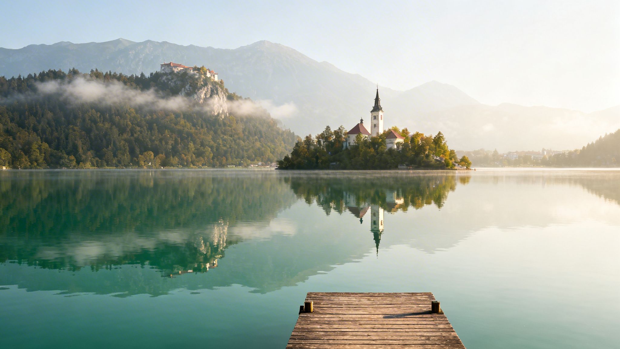 Scenic view of Lake Bled with the iconic church on an island and a castle on a cliff.